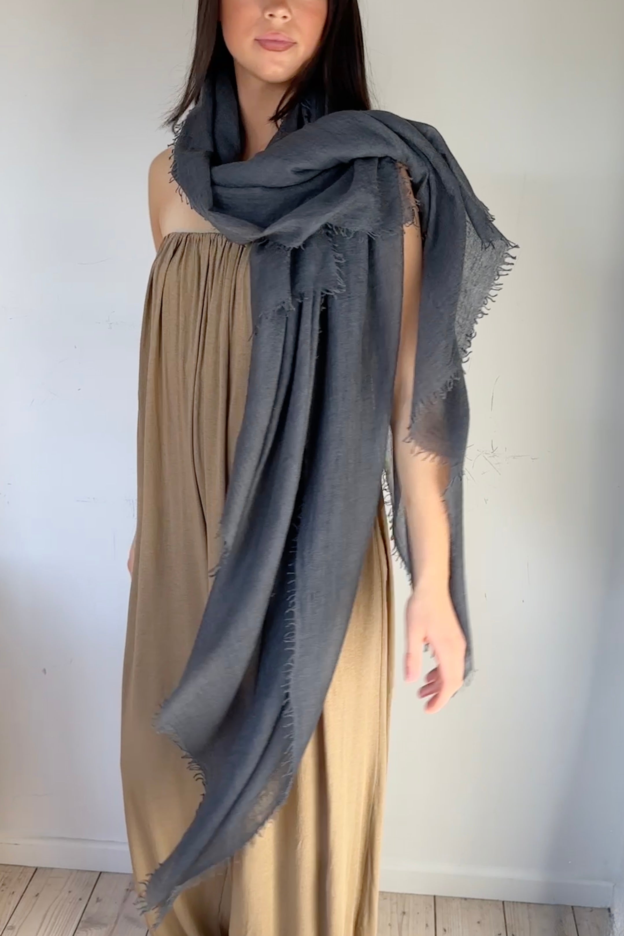 model wearing a large cashmere marmee petrol gray scarf over a beige dress against a white background