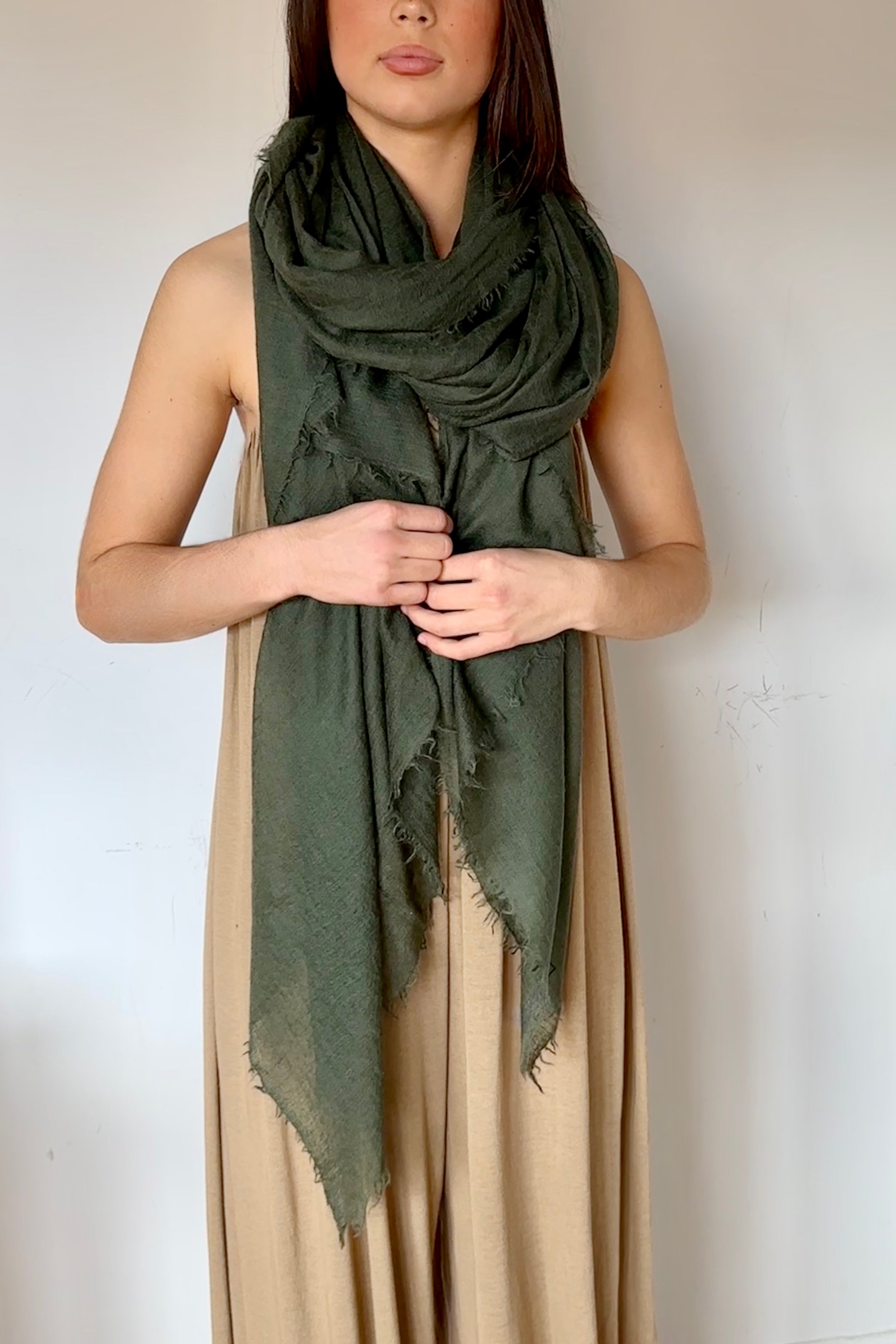 Woman wearing a green scarf and beige dress against a white background