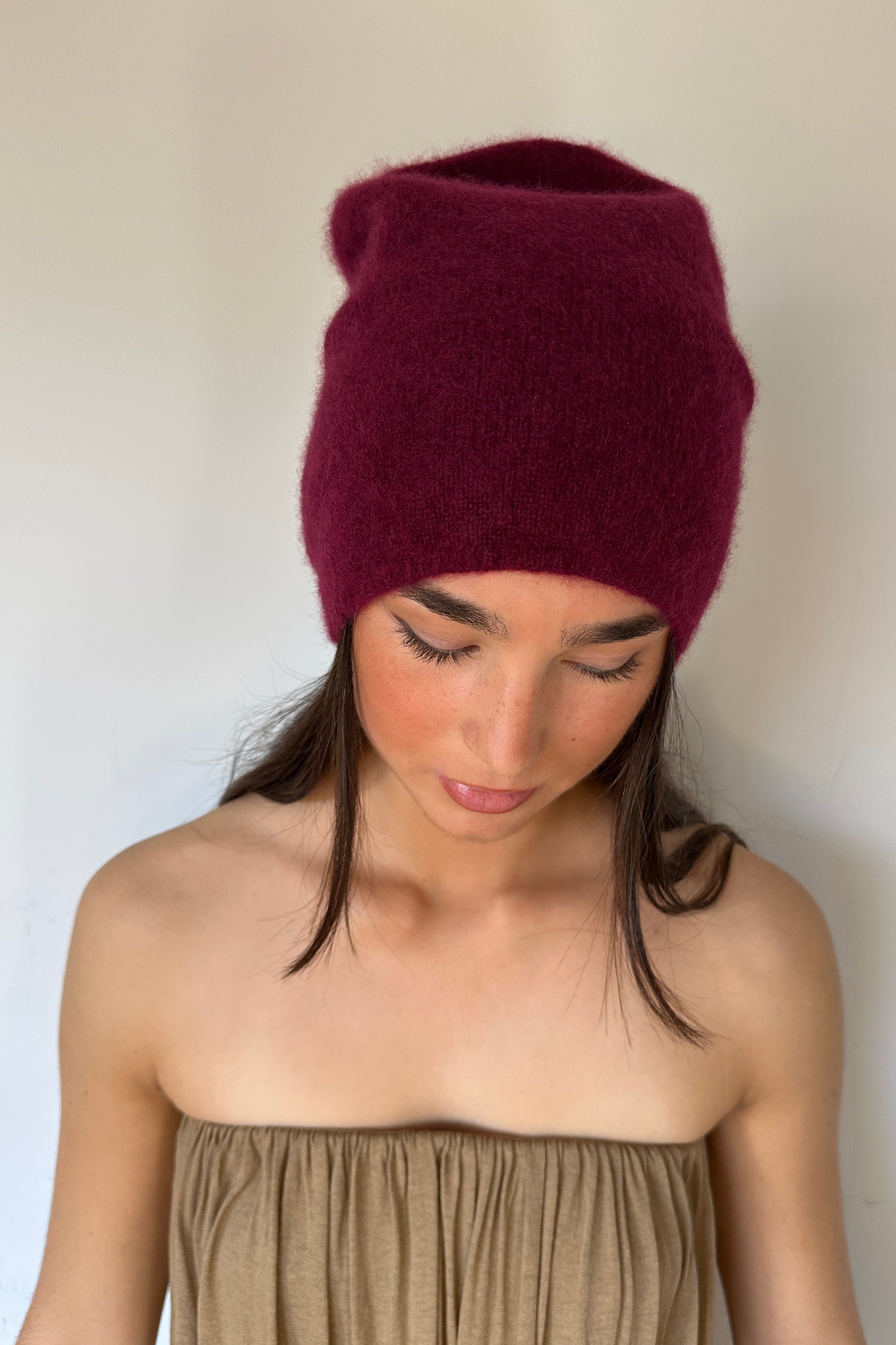 Woman wearing a burgundy knit beanie against a plain background