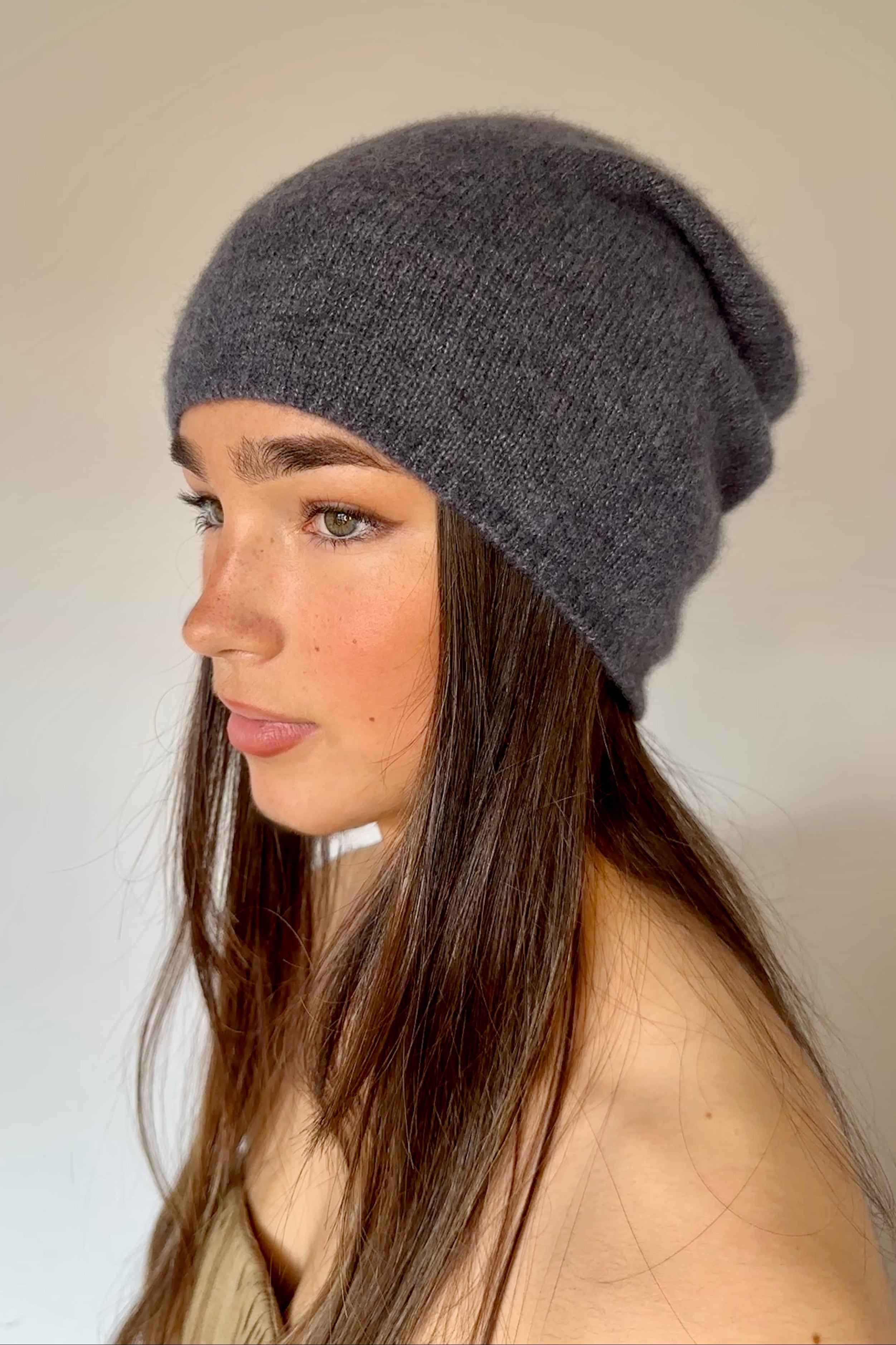 Woman wearing a blue gray knit beanie against a plain background