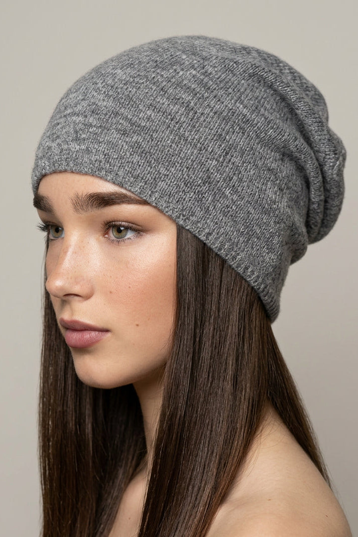 A woman with long brown hair wearing a dark gray knit slouchy beanie hat, shown in profile against a plain light background.