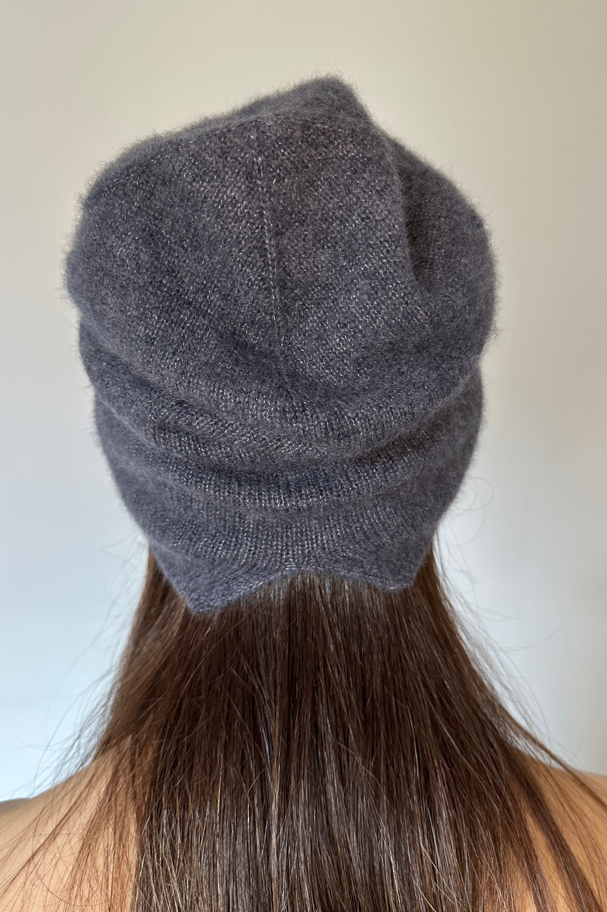 blue Gray knit beanie worn by a person with long hair against a plain background back view