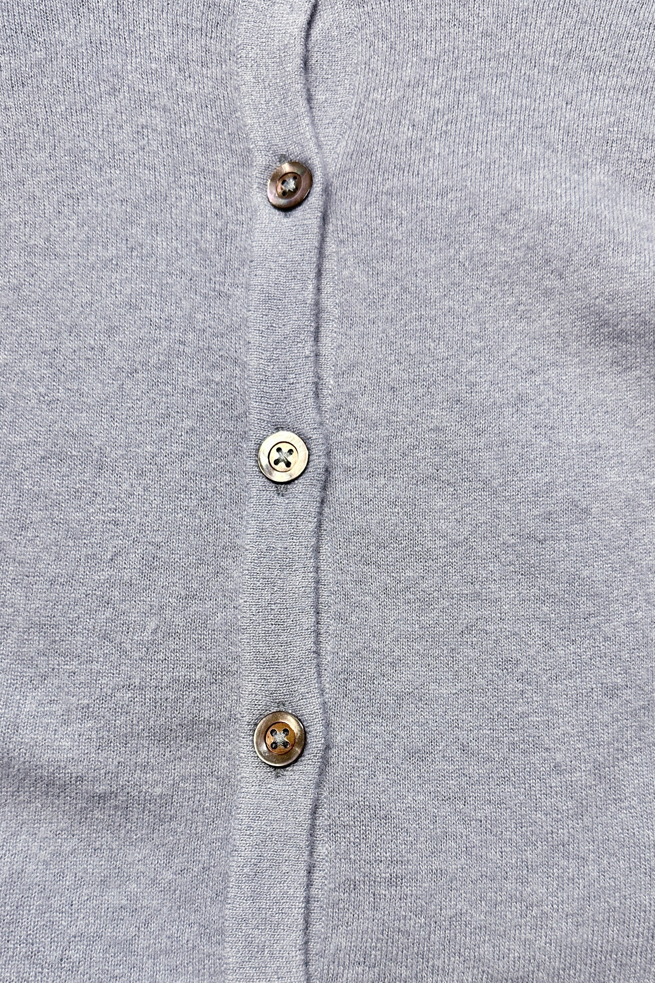 Close-up of a gray button-up cashmere cardigan with visible buttons.
