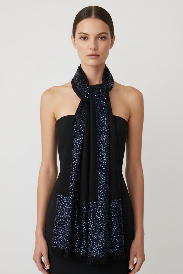 Woman wearing a black sleeveless top with a blue patterned scarf around her neck on a white background