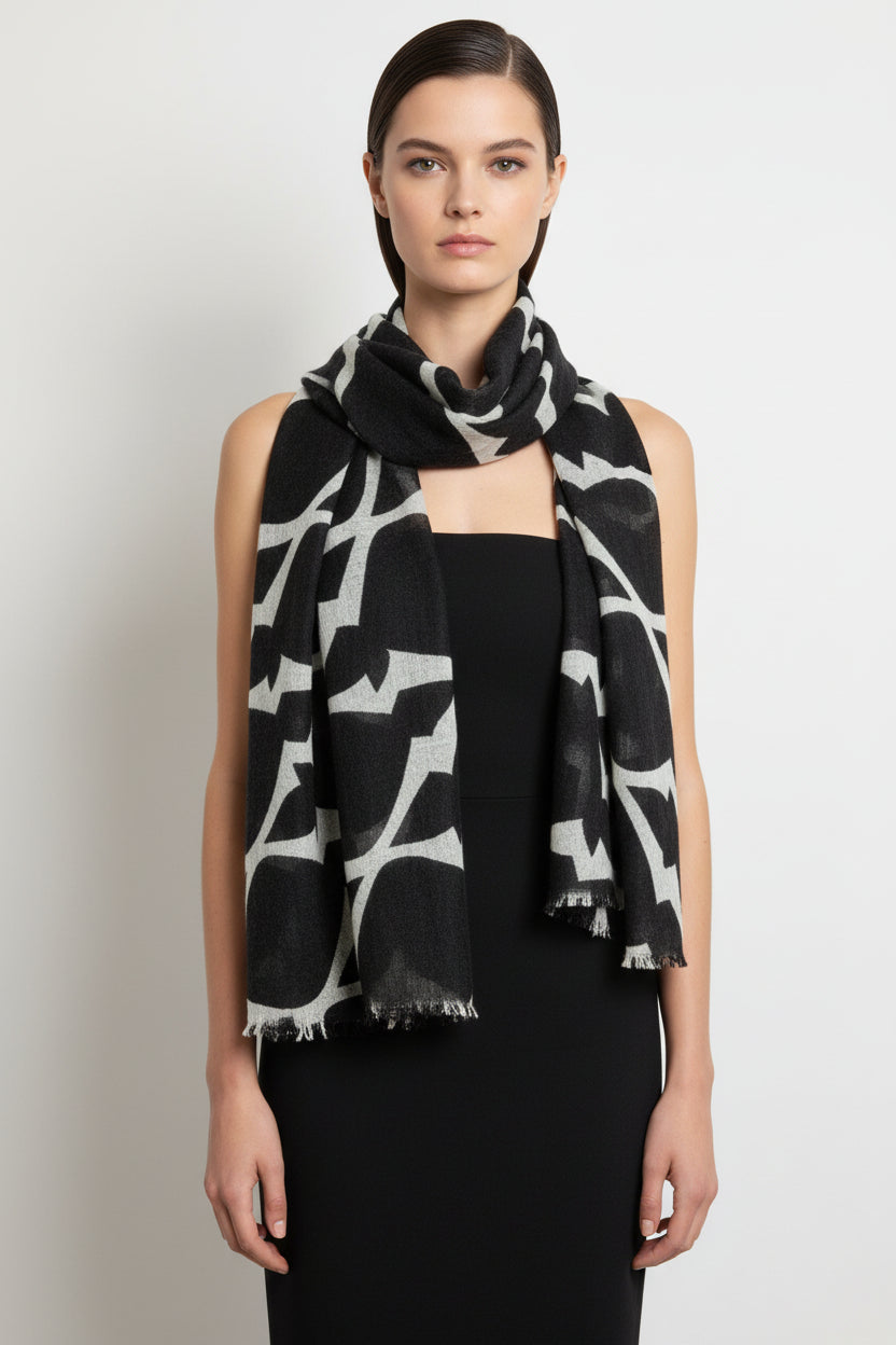 Woman wearing a black and white patterned scarf on a plain background