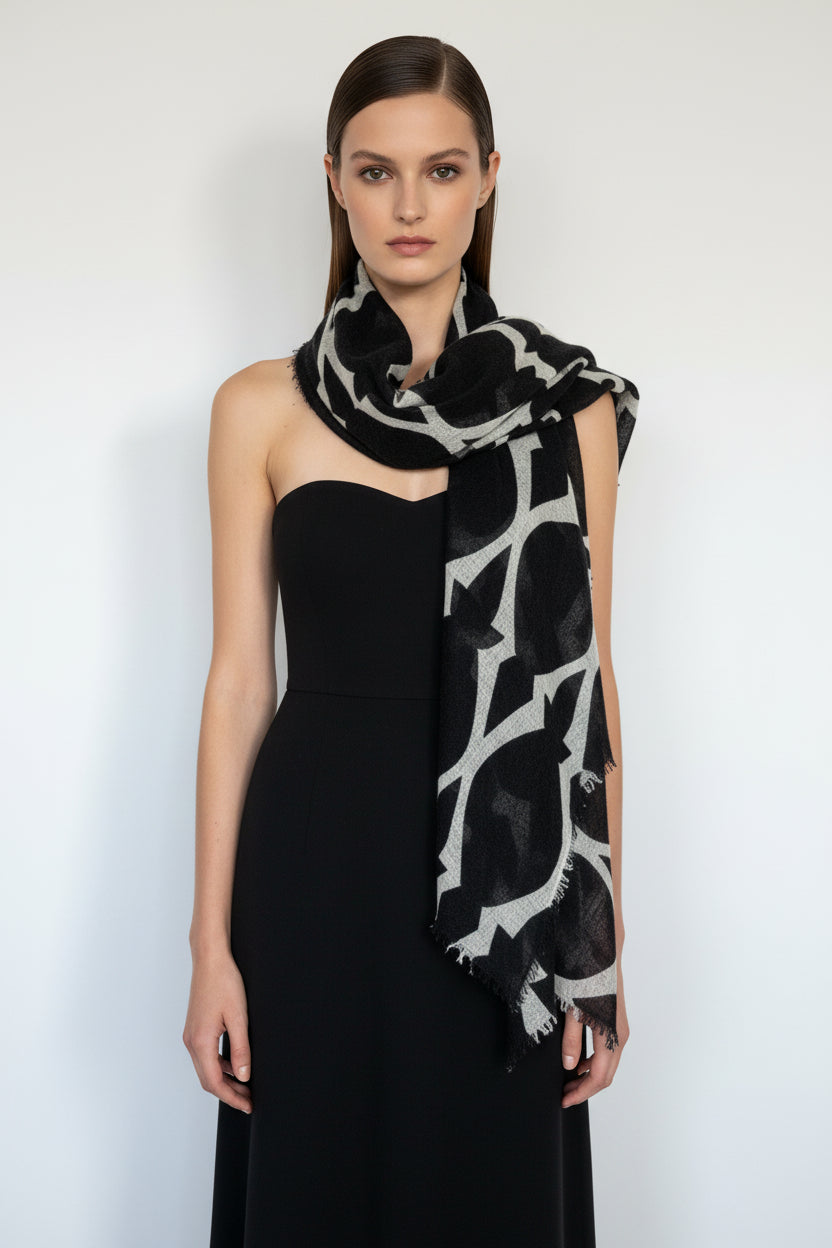 Woman wearing a black dress with a black and white patterned cashmere scarf on a white background