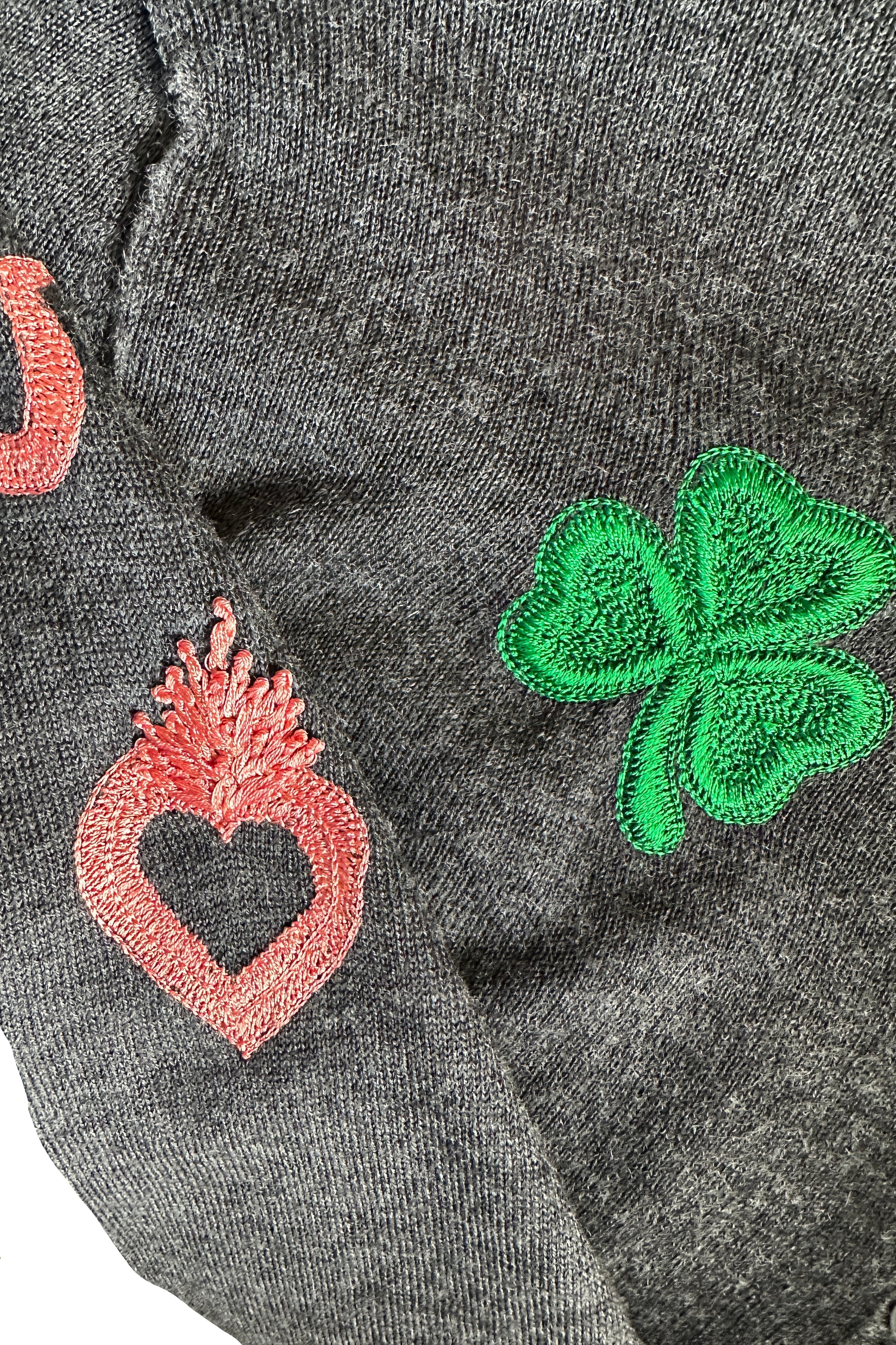 Embroidered green four-leaf clover and pink heart on a gray fabric background