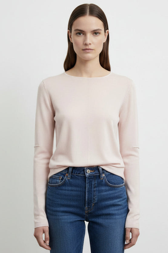 Woman wearing a light pink sweater and blue jeans on a white background
