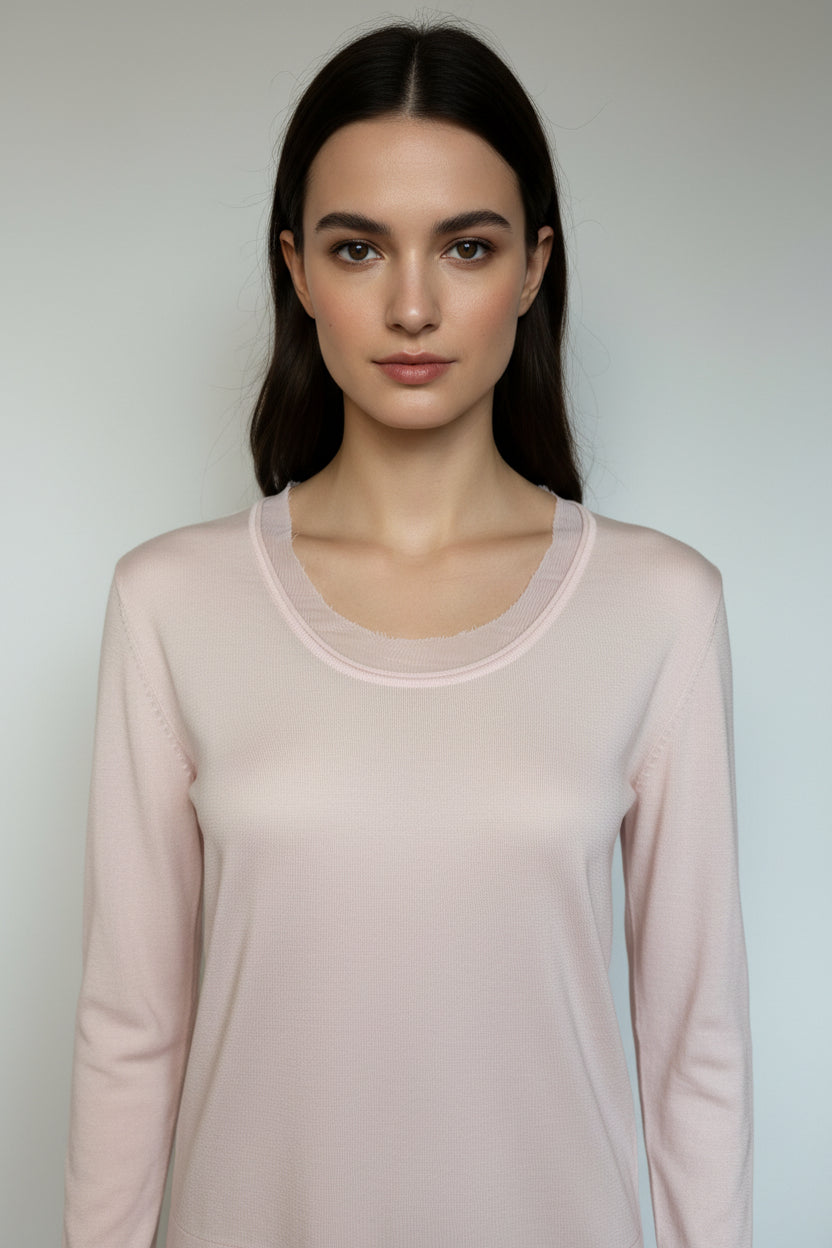 Woman wearing a light pink long-sleeve top against a plain background
