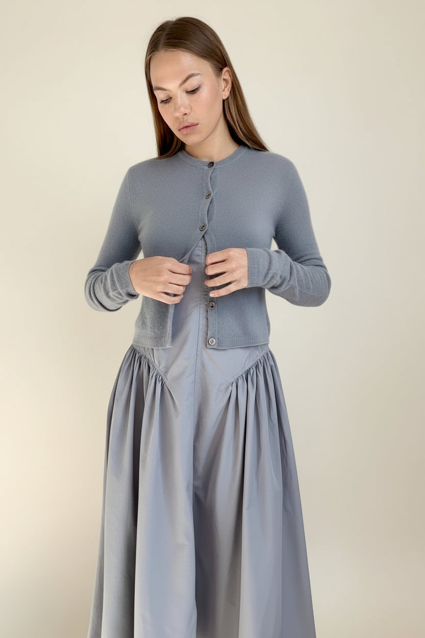 Woman wearing a gray cardigan and skirt set against a plain background