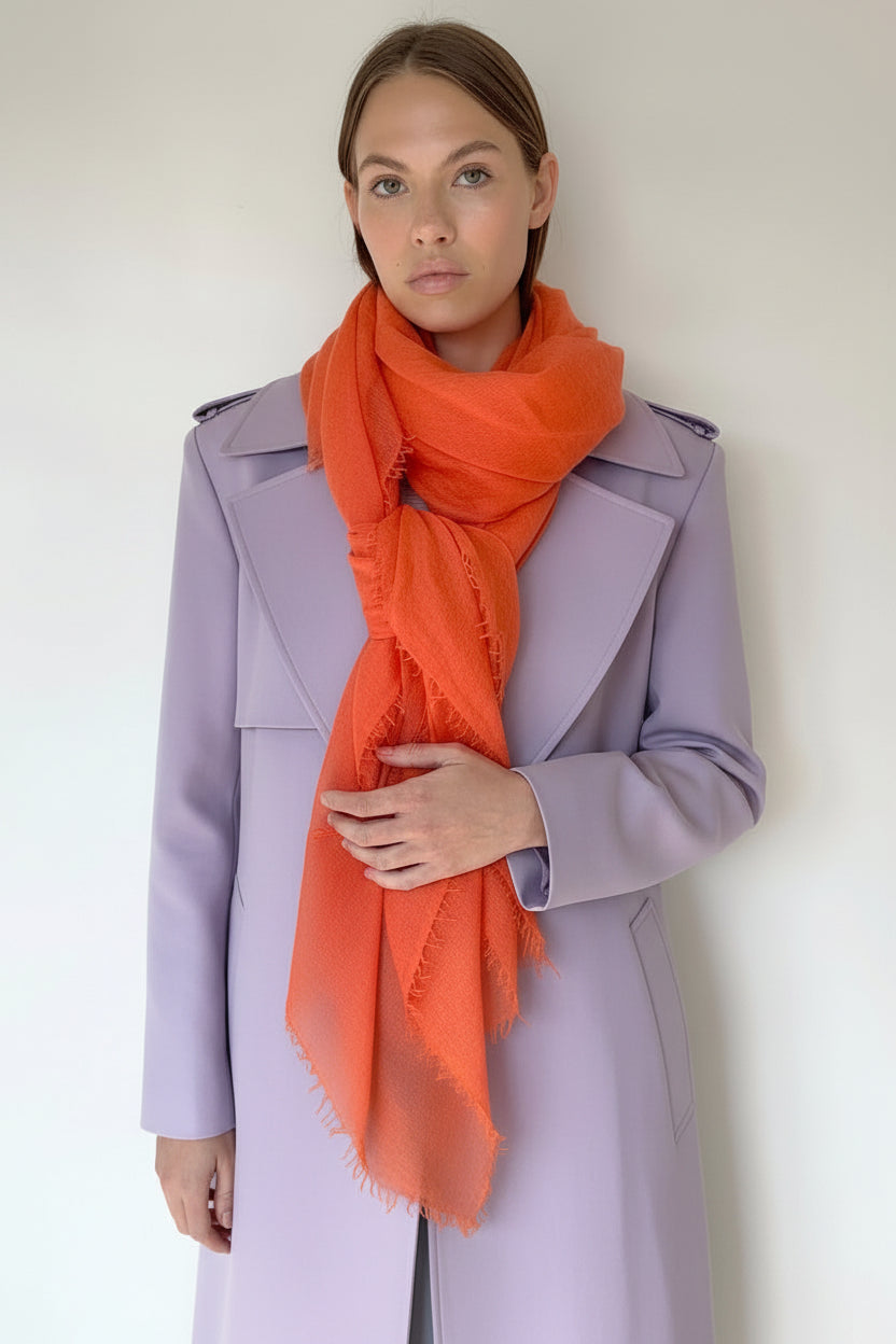 Woman wearing a striped cardi and orange scarf against a plain background
