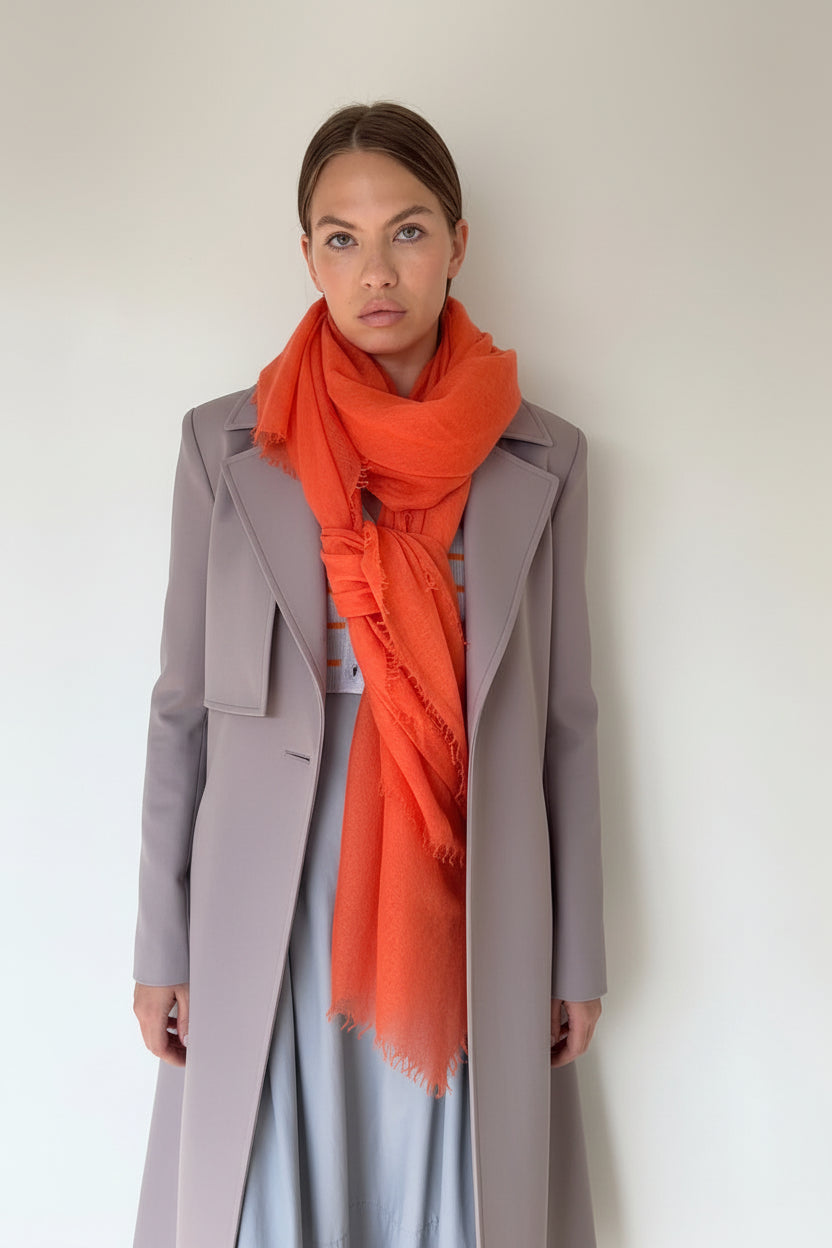 Woman wearing a striped sweater and orange scarf against a plain background