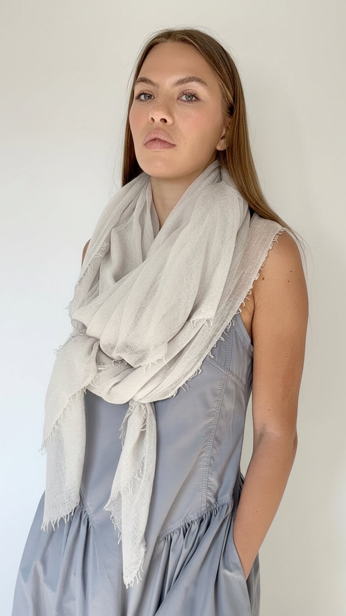 Woman wearing a light gray scarf and a gray dress against a white background