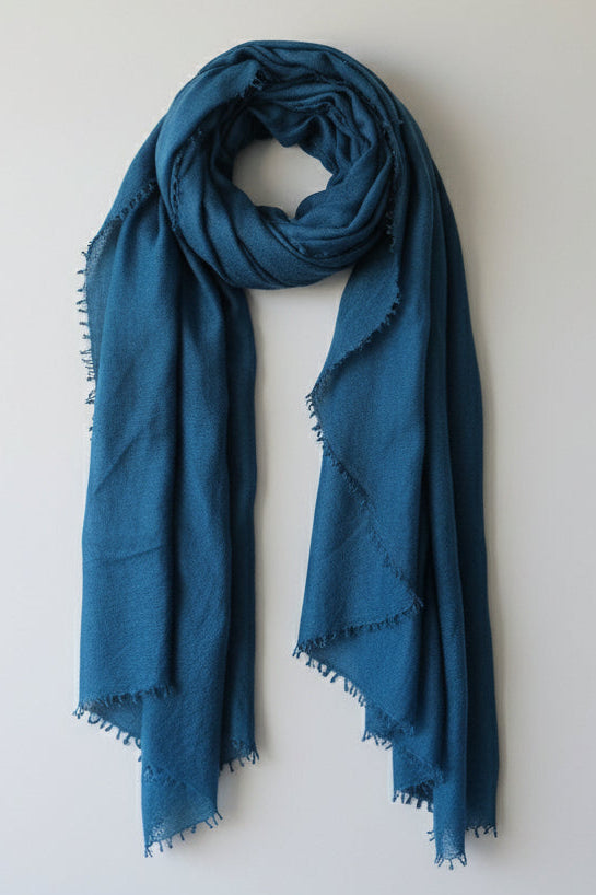 flat lay marmee teal blue scarf against a plain background