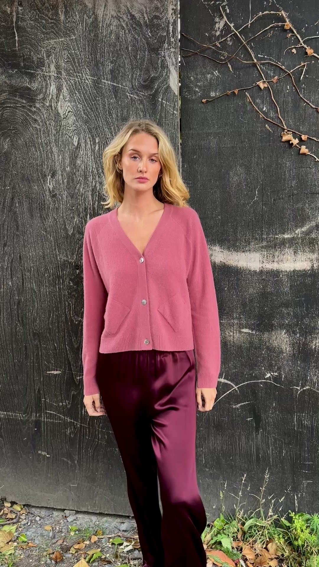 model wearing a zola rose pink cardigan against a textured dark background