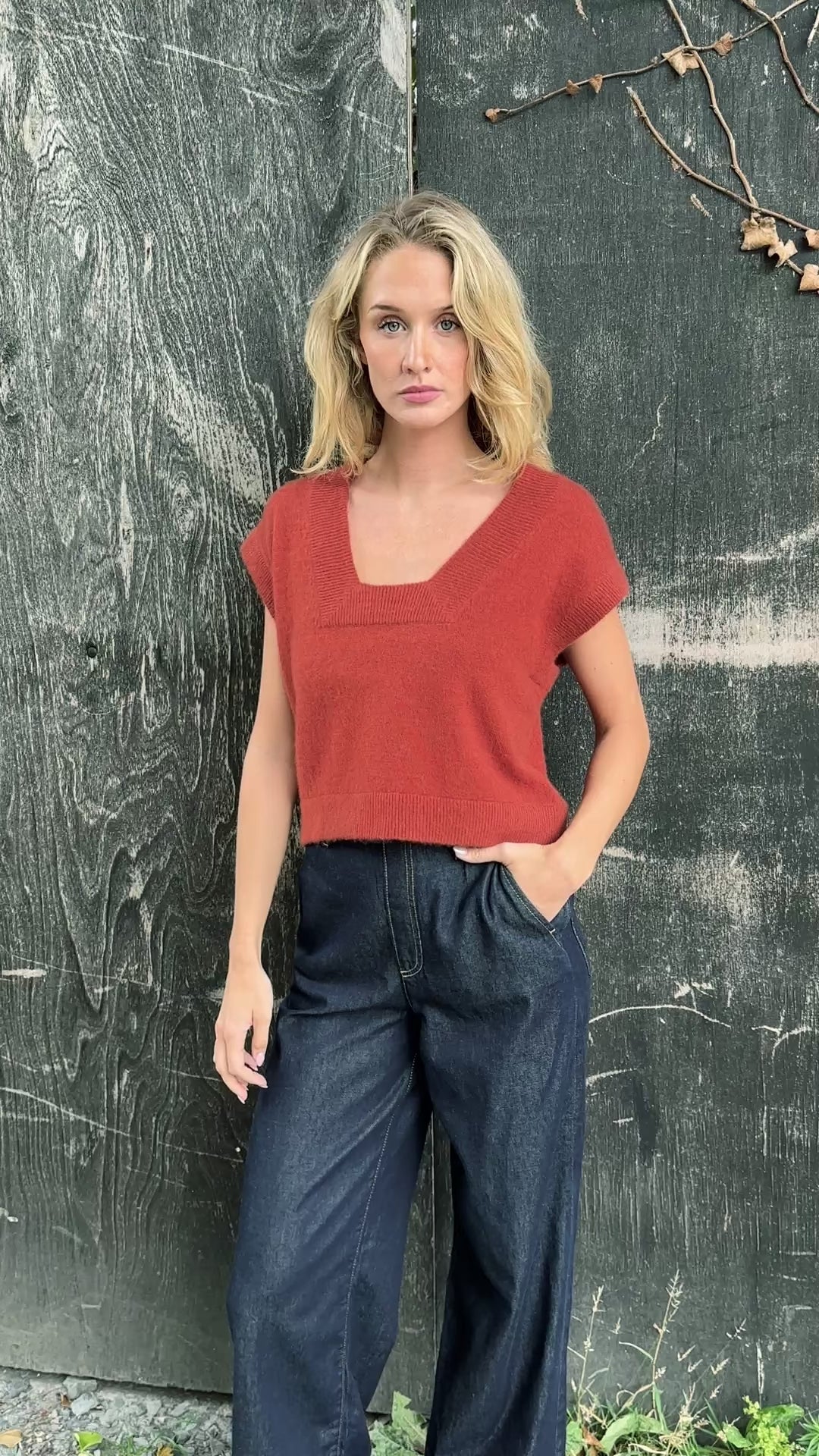 model wearing a rust-colored cashmere square neck knit tank top against a dark background