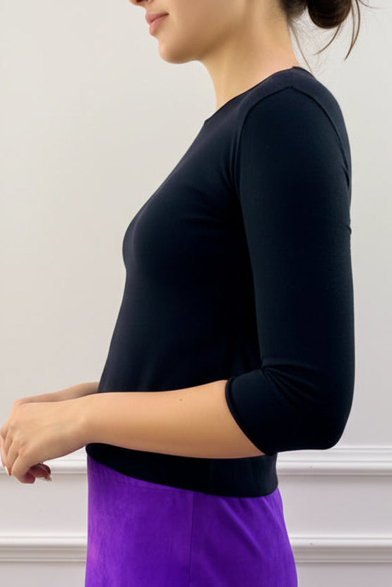 Model wearing a black cashmere silktop and purple skirt against a plain background