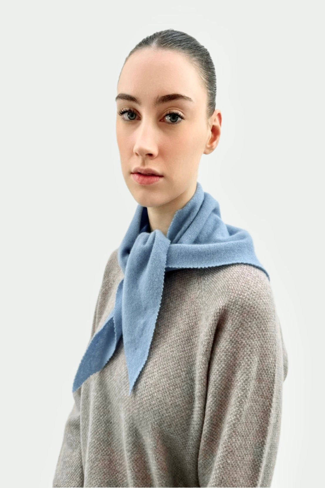 Woman wearing a Doon light blue scarf around her neck against a white background