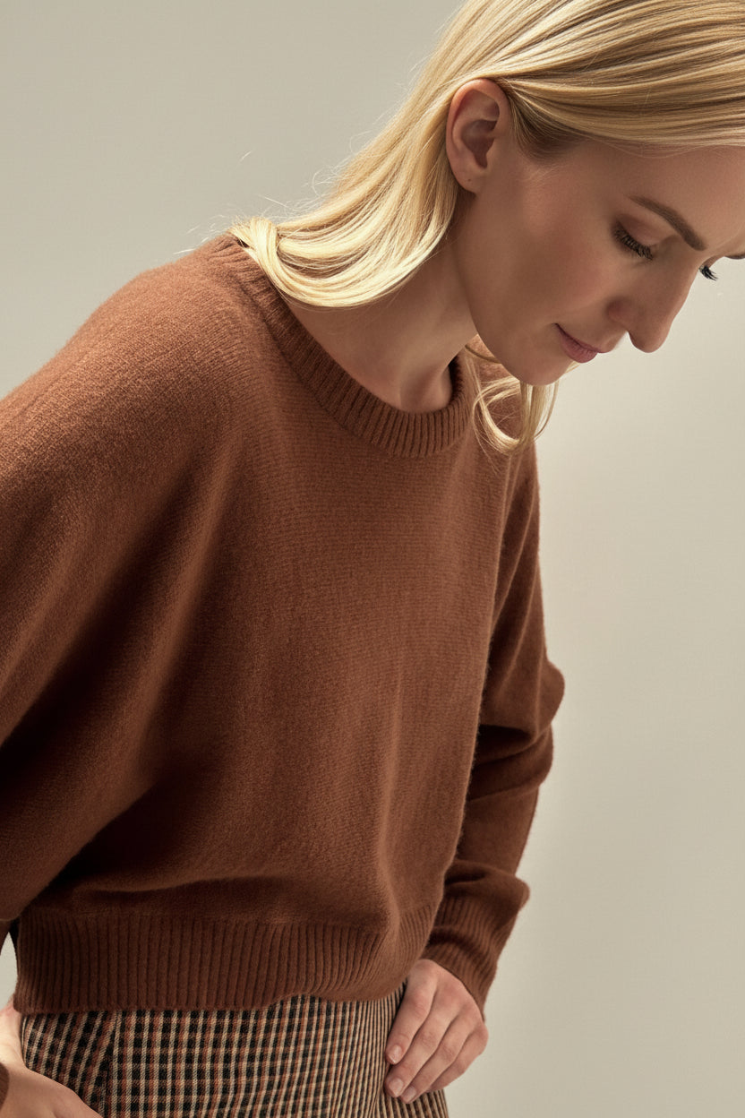 Person wearing a brown sweater against a neutral background