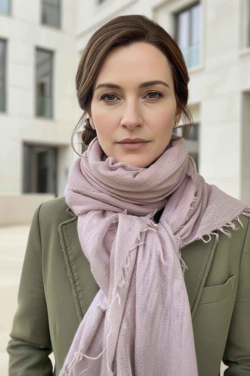 Woman wearing a pink scarf and green jacket outdoors.