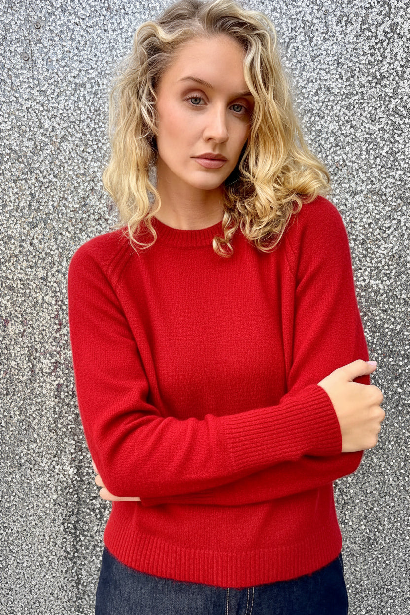 Woman wearing a red sweater against a textured wall