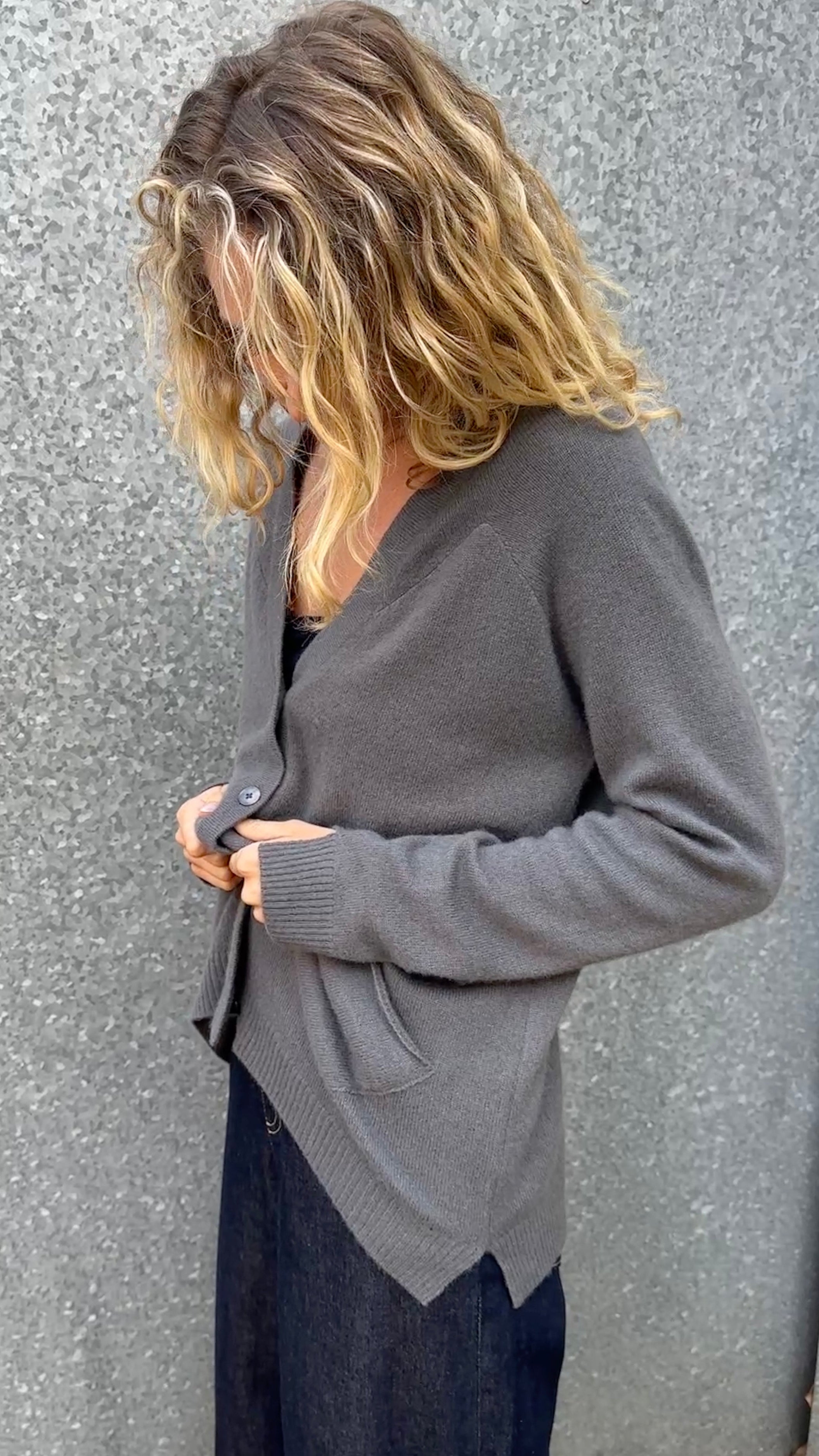 model wearing a  Zola gray cardigan  grey cashmere against a textured wall