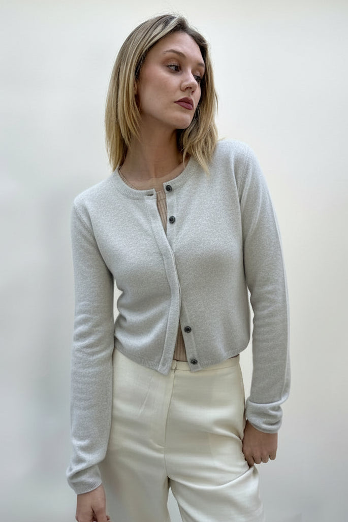 Woman wearing a cream-colored cardigan and pants against a white background