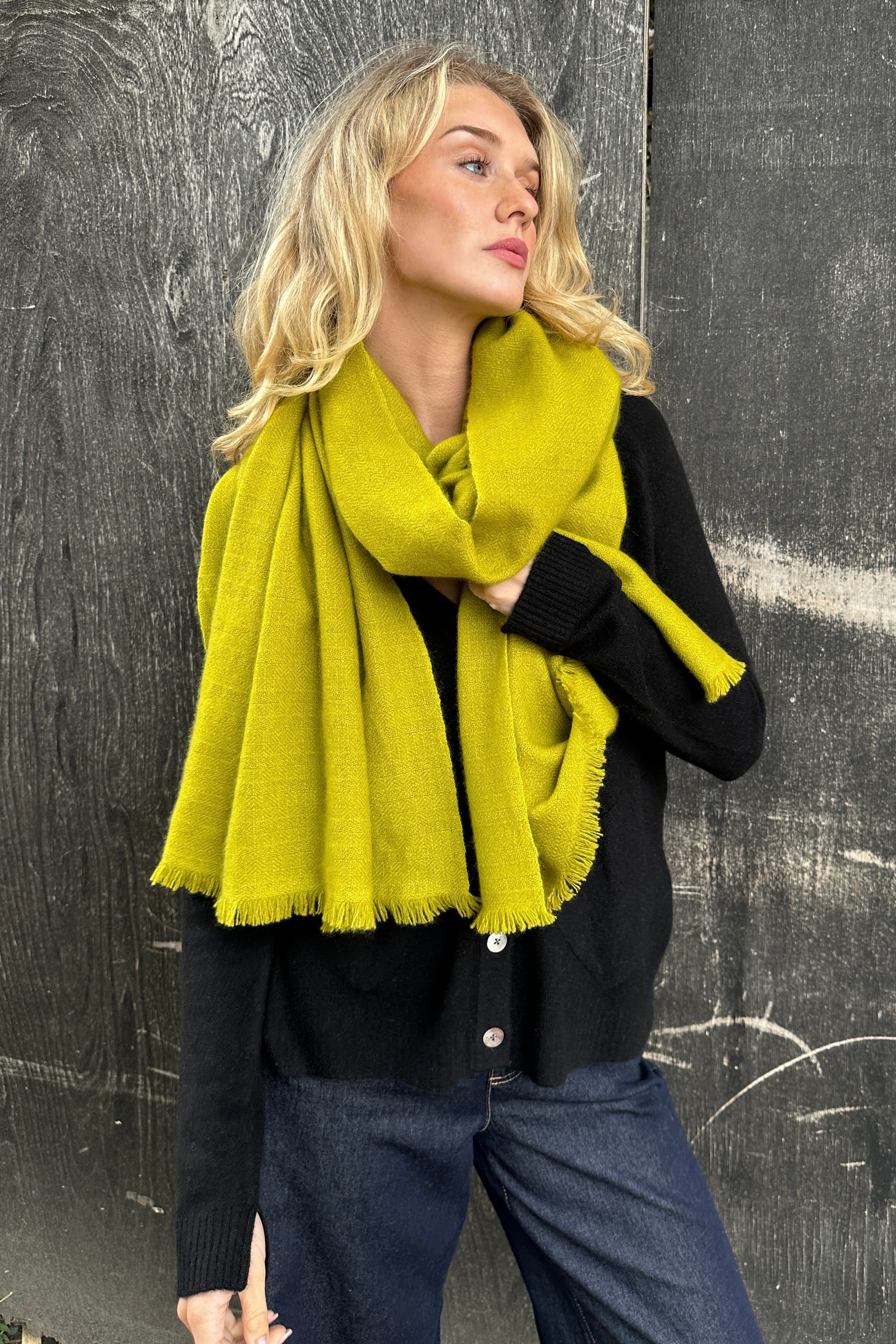 Woman wearing a bright yellow scarf against a dark background