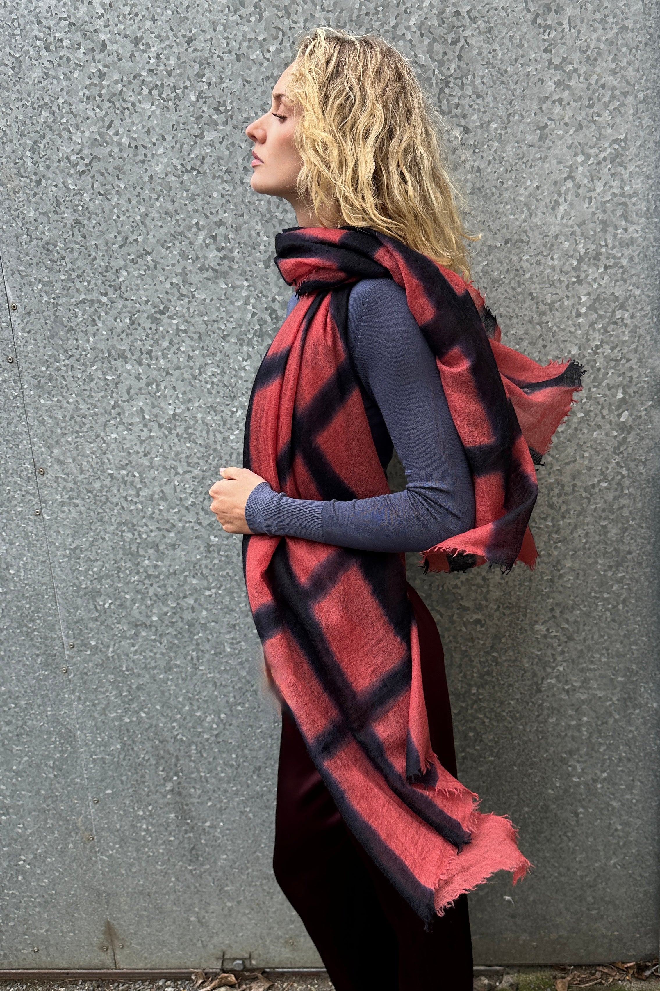 Woman wearing a red and black plaid scarf against a gray wall