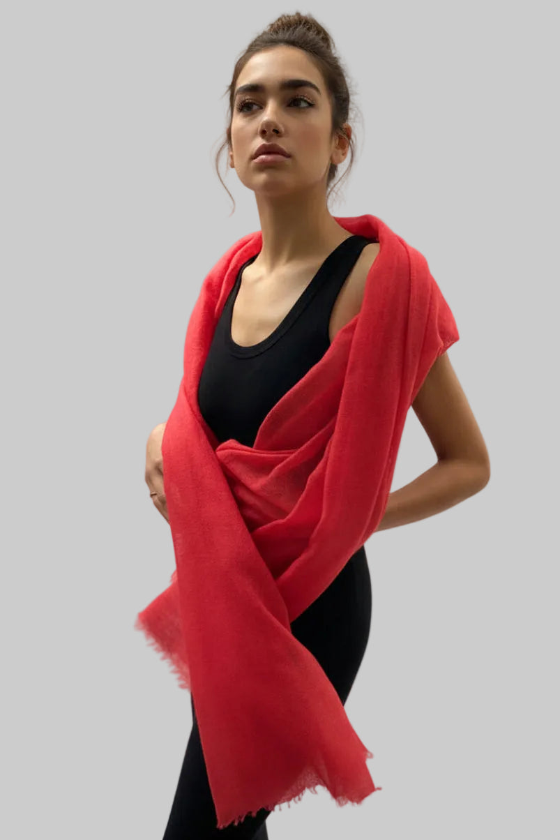 Person wearing a bright red scarf over a black top against a white background
