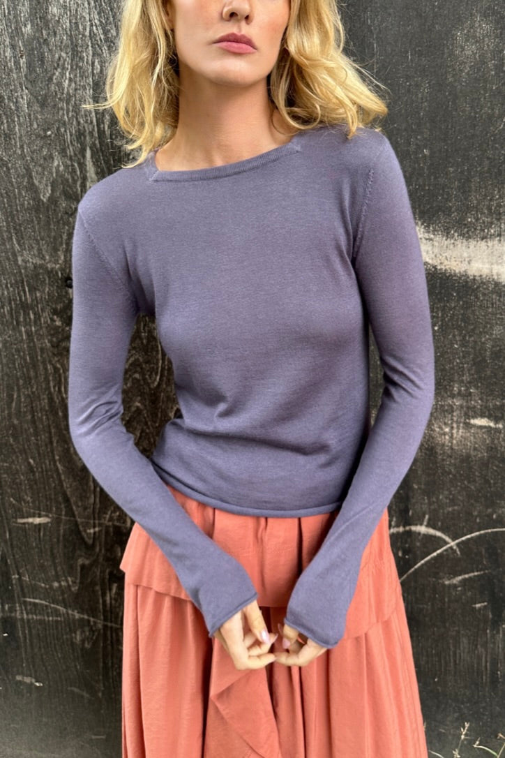 Model wearing a purple  lassa square neck long-sleeve top and pink skirt against a textured black background