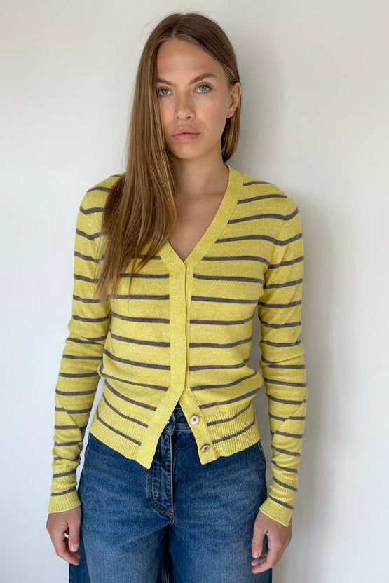 Woman wearing a yellow striped cardigan against a white wall