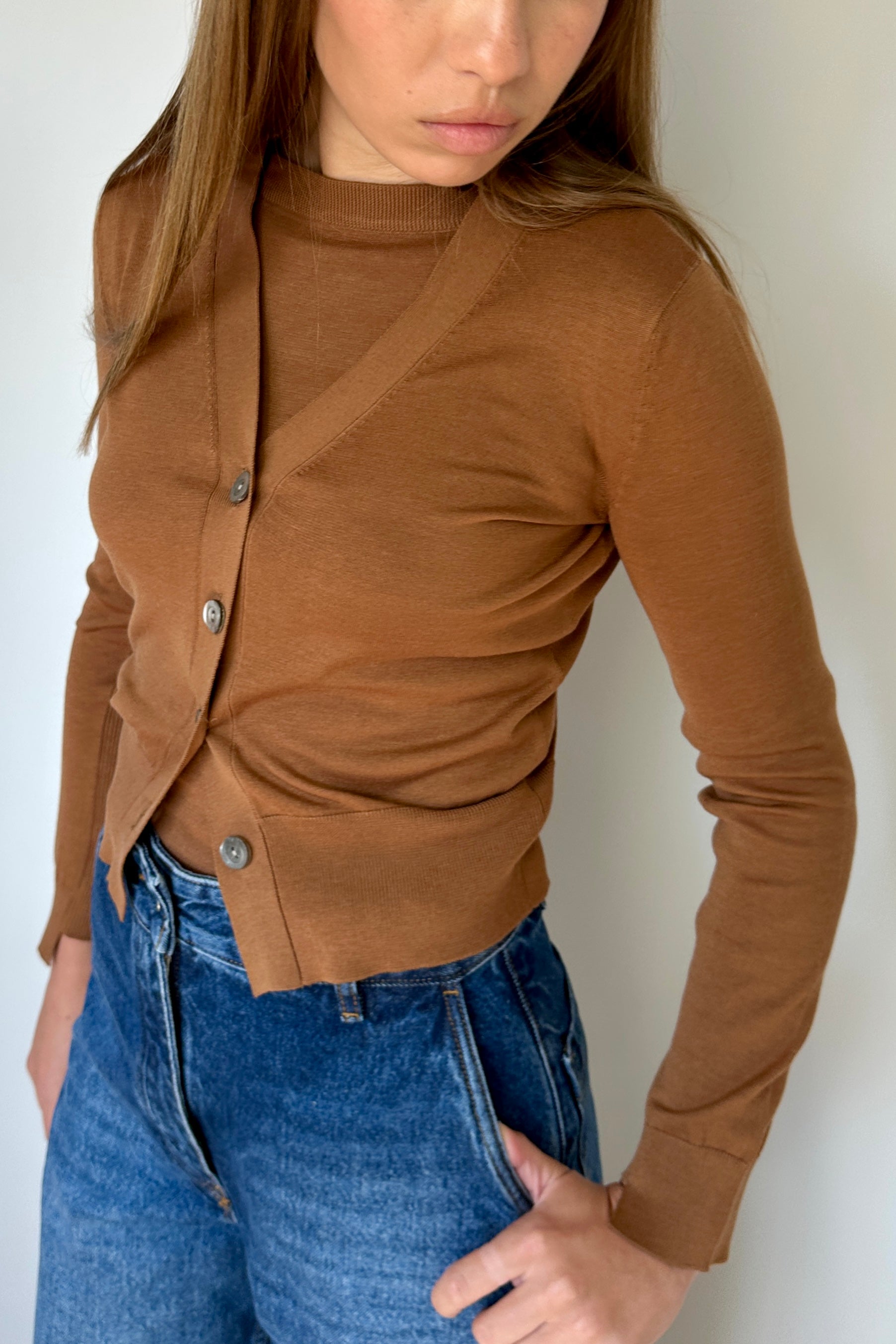 Woman wearing a brown button-up top and blue jeans against a white background