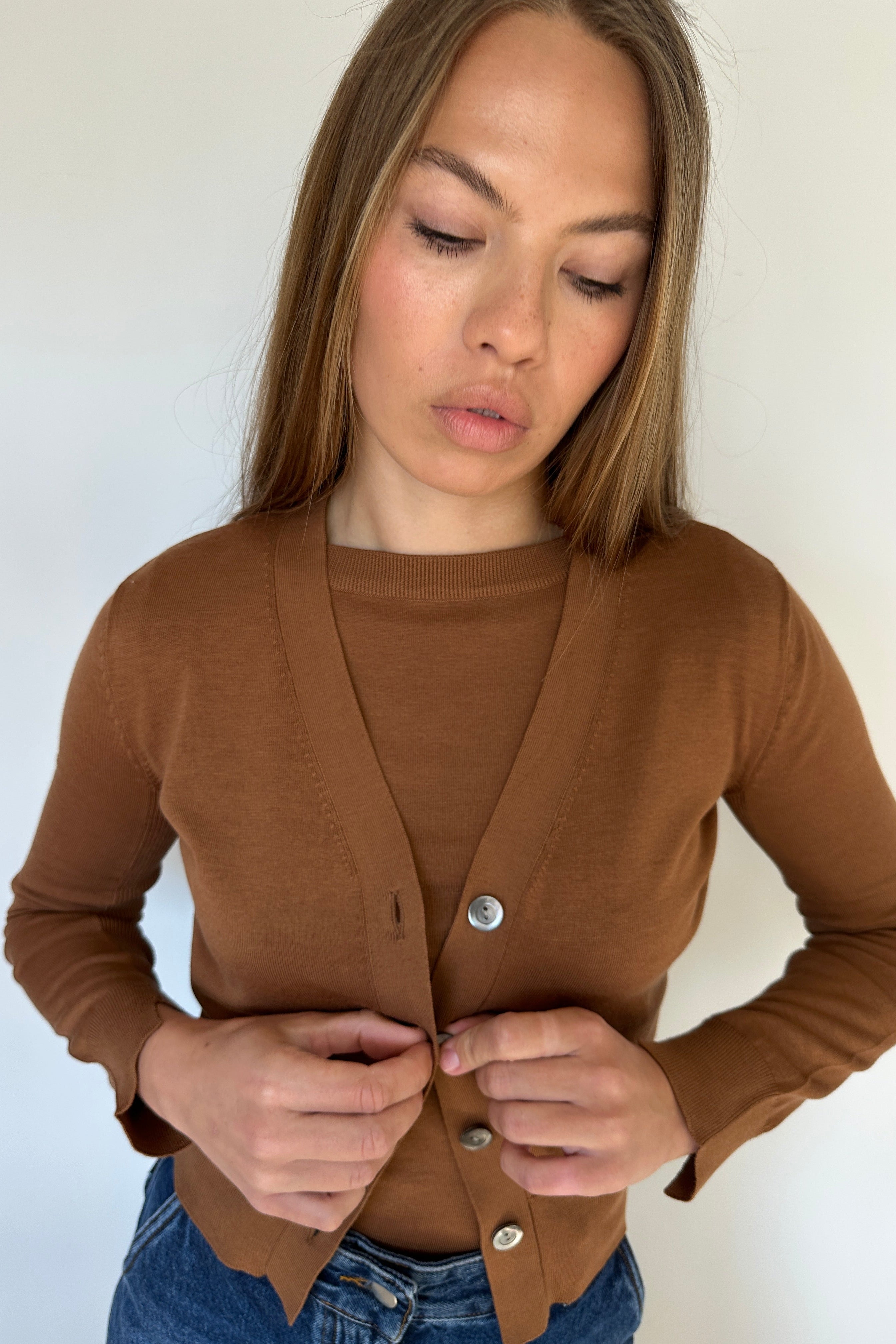 Woman wearing a brown carrdi on a white background