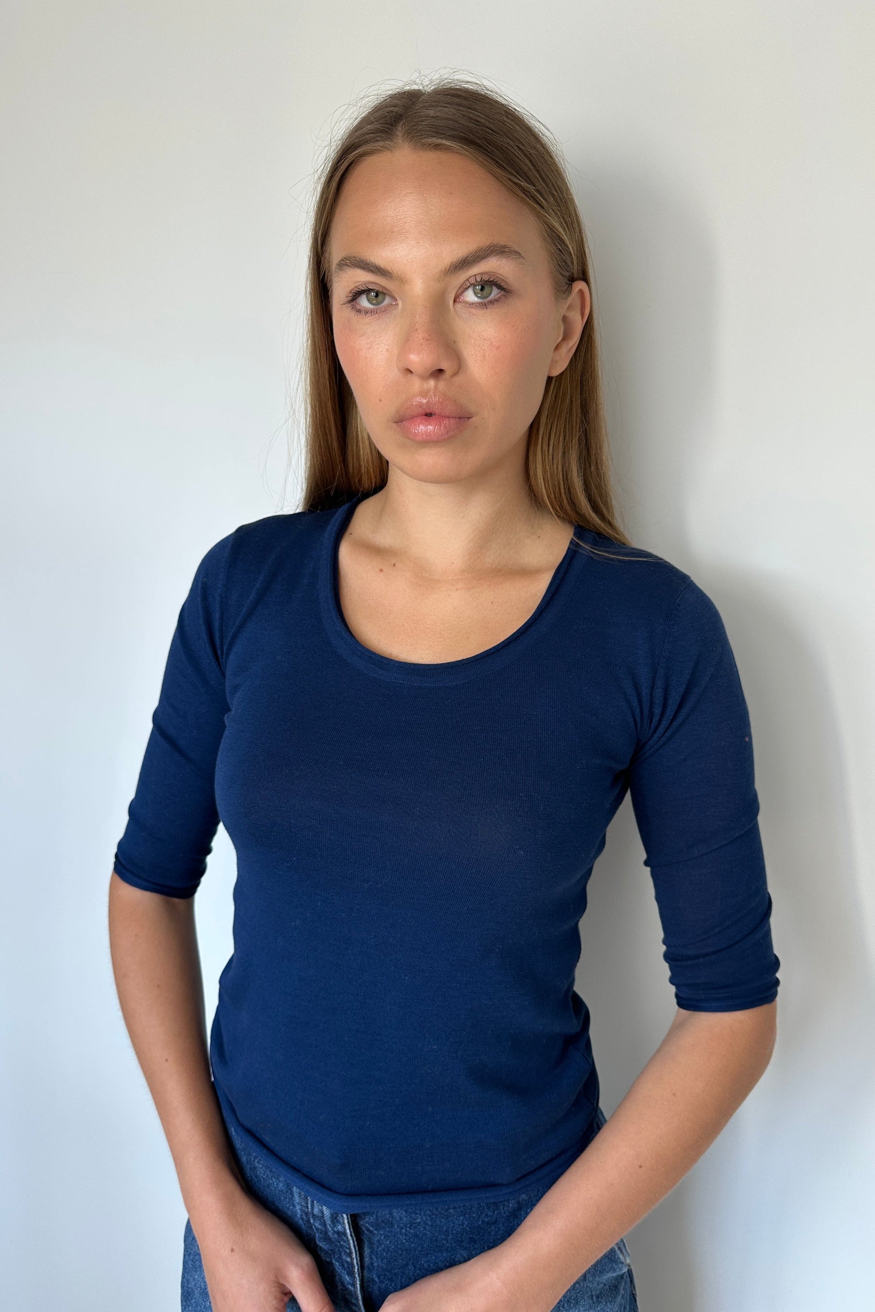 Person wearing a blue long-sleeve shirt against a white background