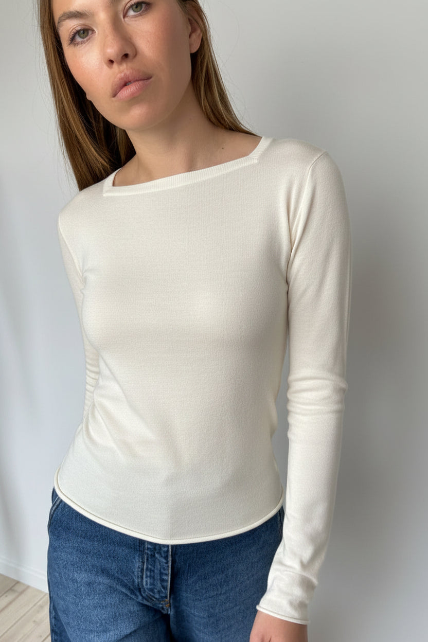 Person wearing a white long-sleeve top and jeans against a white background