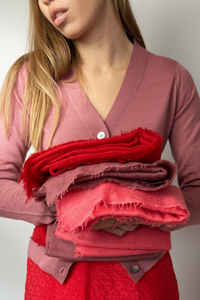 Woman holding folded red and pink fabric against a plain background