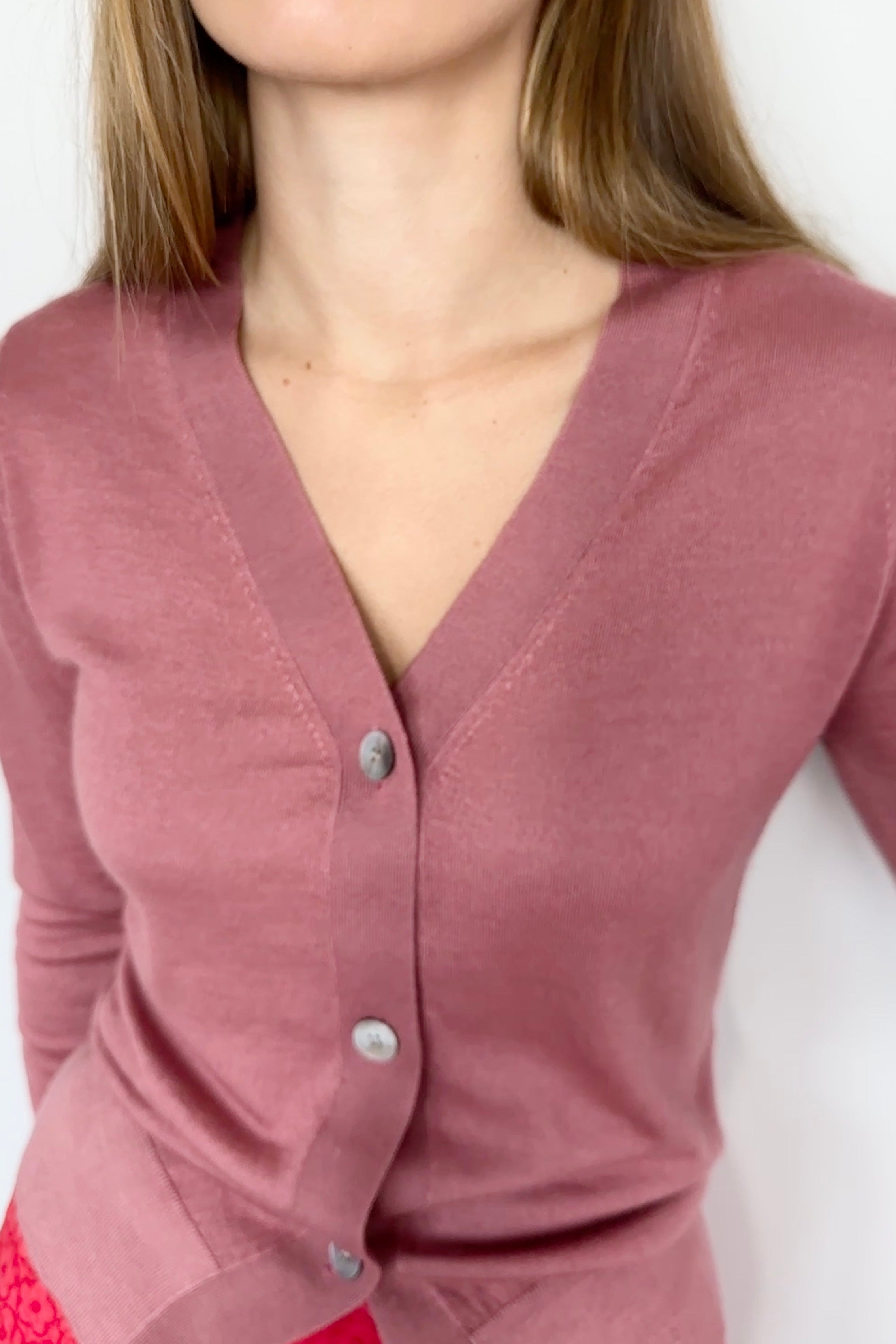 Woman wearing a pink cardigan against a white background