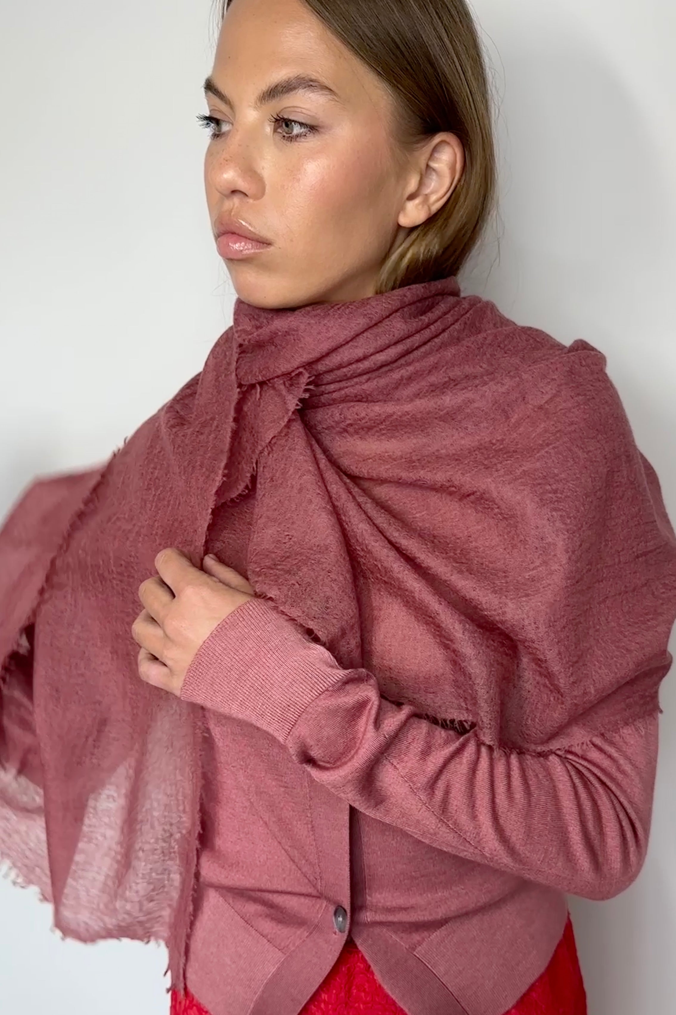 Woman wearing a mauve jacket with a red skirt against a white background