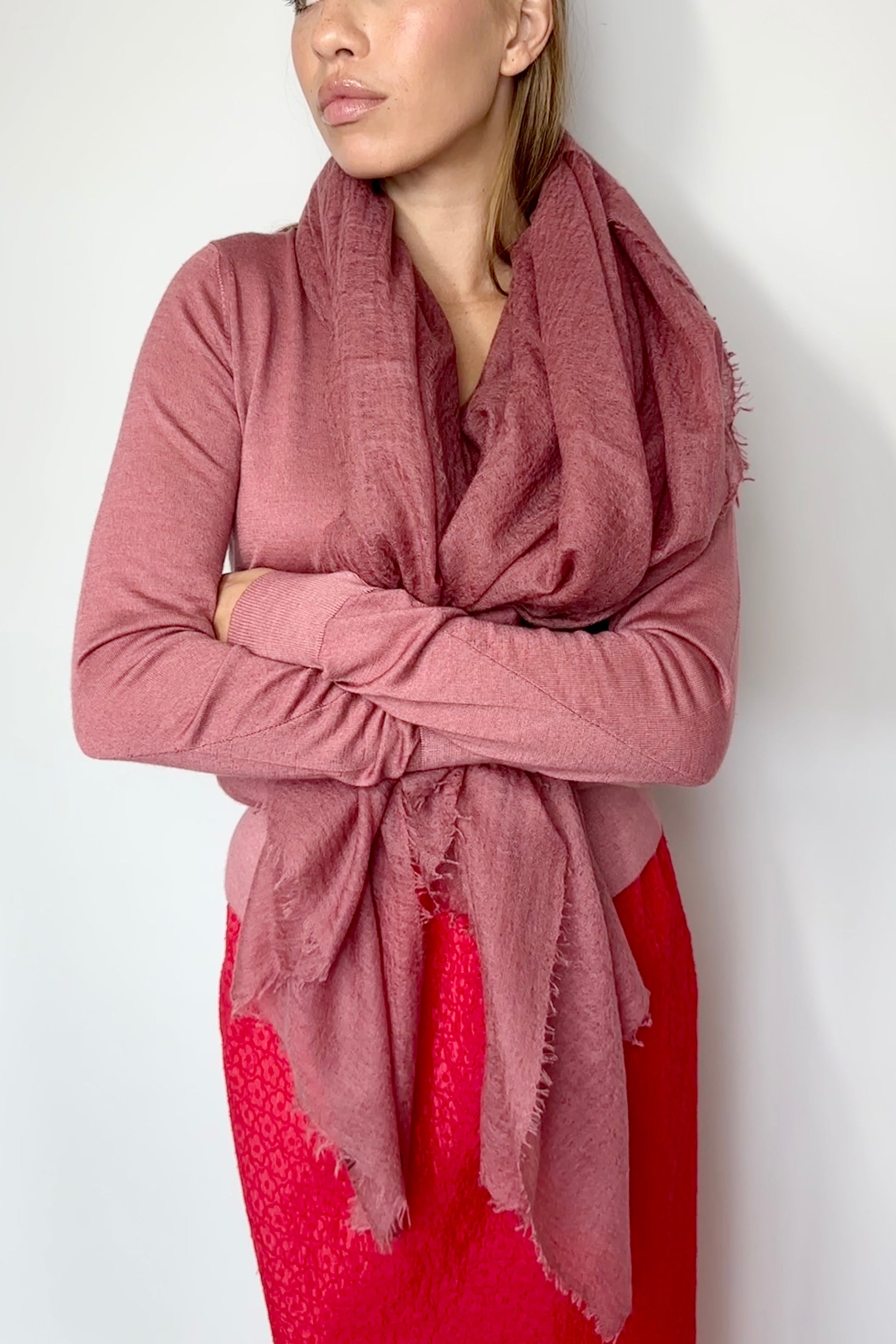 Woman wearing a pink scarf and red dress against a white background