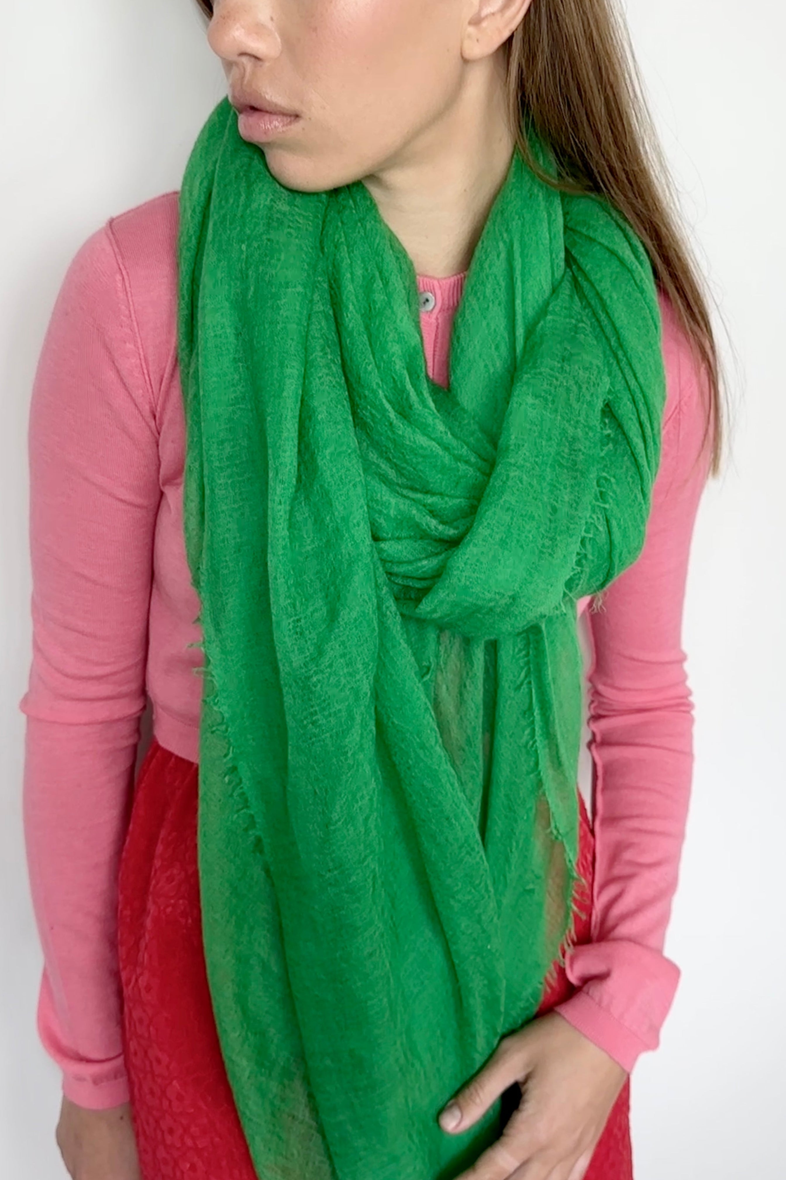 Woman wearing a green scarf and red pants against a white background