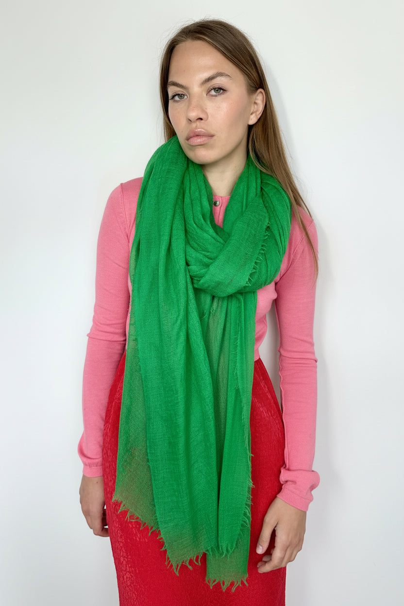 Woman wearing a green scarf and pink shirt against a white background