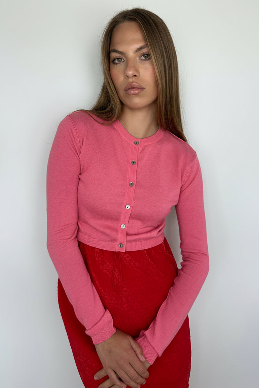 Woman wearing a pink jacket over a red garment on a white background