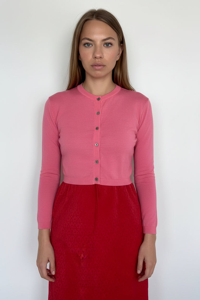 Woman wearing a pink long-sleeve top and red skirt against a white background