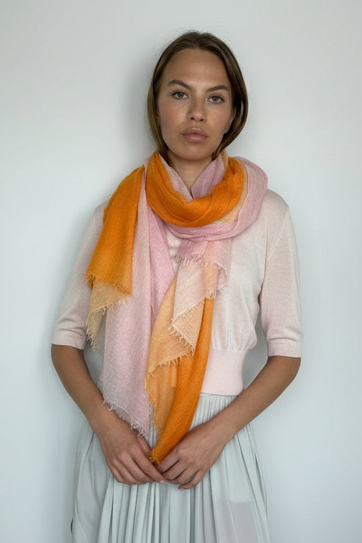 Woman wearing a pink / orange scarf against a plain background