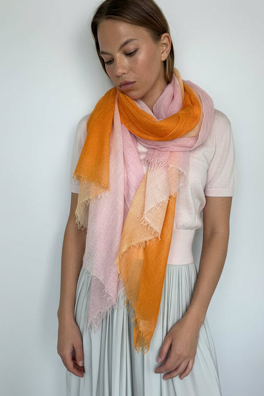 Woman wearing a pink orange scarf with a plain background