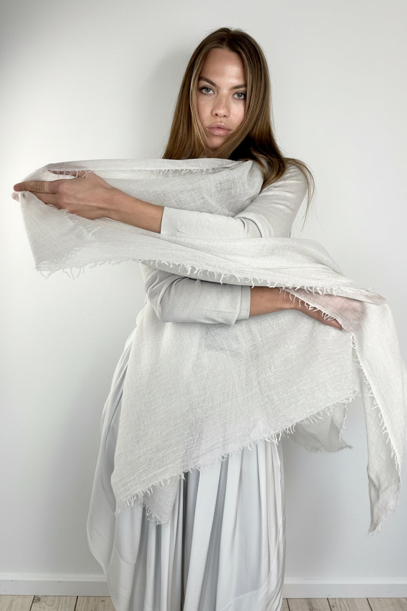 Woman holding a white scarf against a plain background