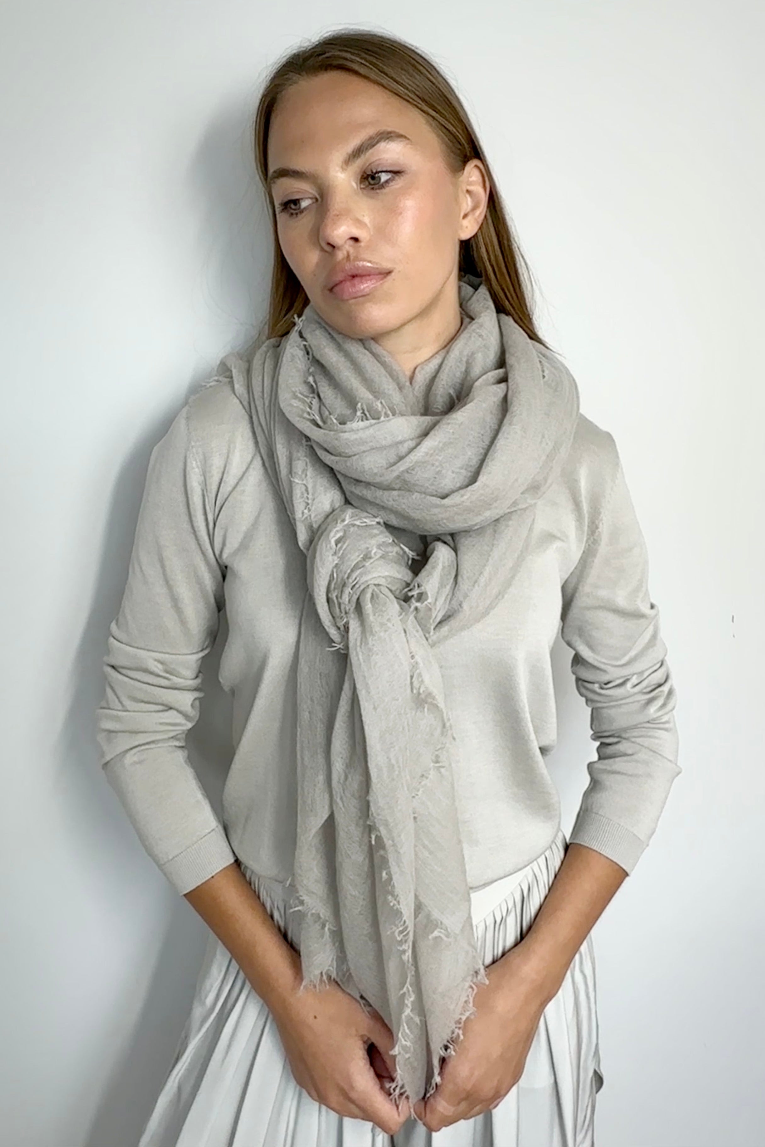 Woman wearing a light gray scarf against a white background