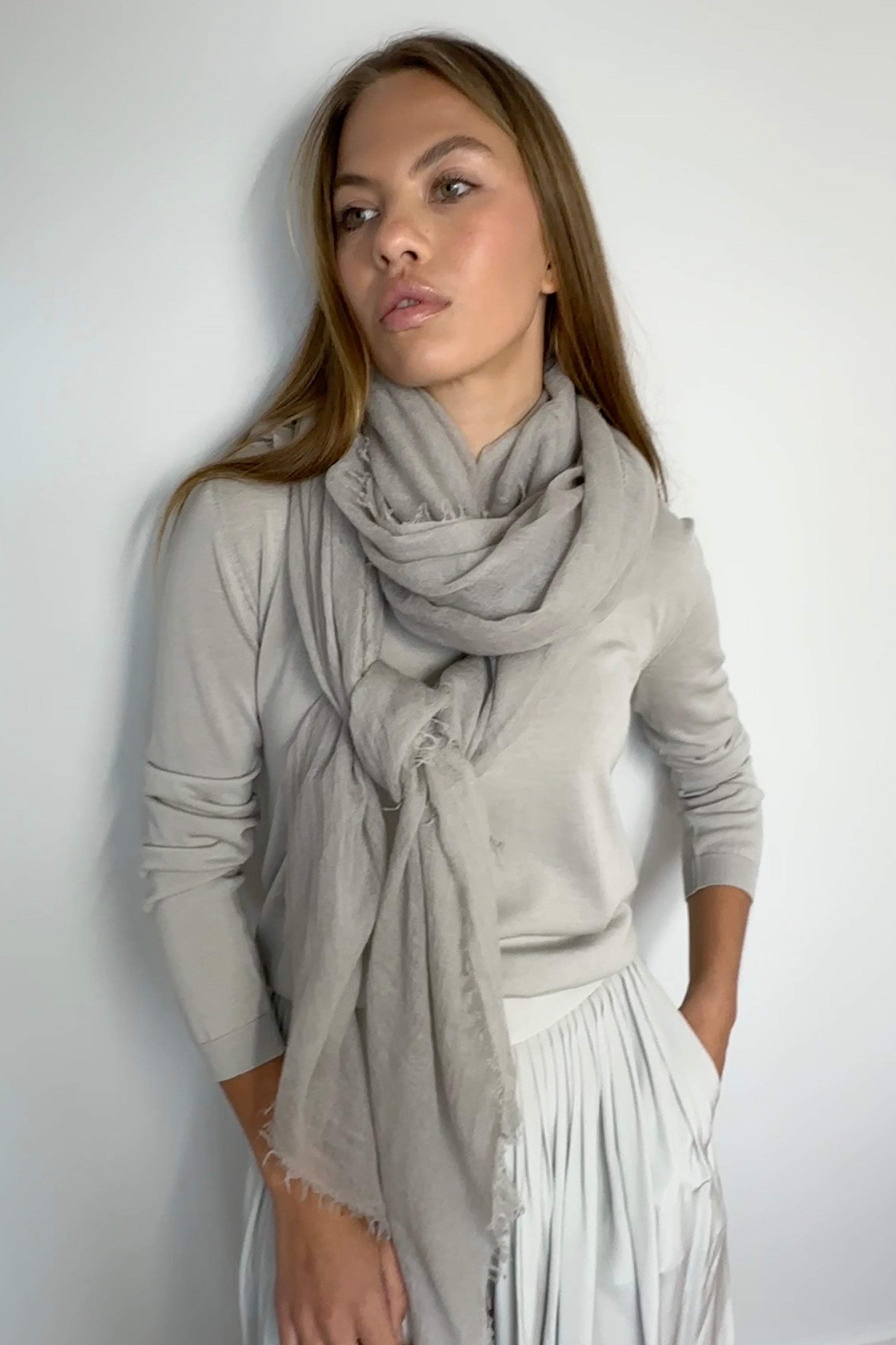 Woman wearing a light gray scarf against a white background
