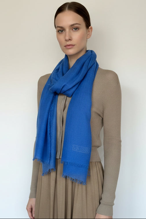 Woman wearing a blue scarf with a neutral background